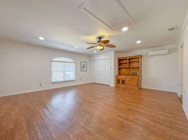 unfurnished living room with visible vents, baseboards, light wood-style floors, a wall mounted AC, and attic access