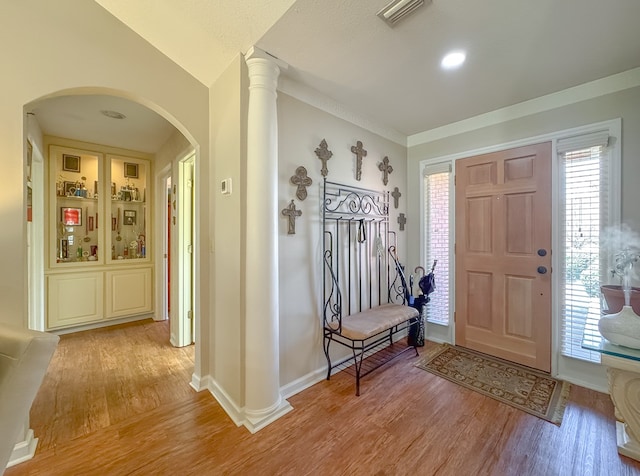 entryway featuring decorative columns, visible vents, arched walkways, baseboards, and light wood-style flooring