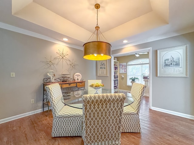 dining area featuring a tray ceiling, wood finished floors, and baseboards