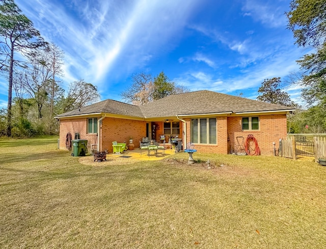 back of property with a patio area, brick siding, a yard, and a fire pit