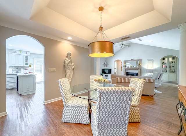 dining area with a tray ceiling, light wood-type flooring, and visible vents