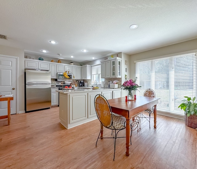 dining area featuring recessed lighting, visible vents, light wood-style flooring, and a textured ceiling