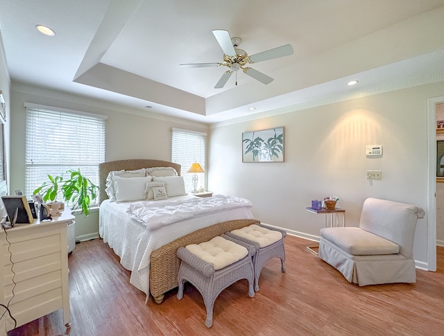 bedroom featuring a tray ceiling, recessed lighting, a ceiling fan, wood finished floors, and baseboards