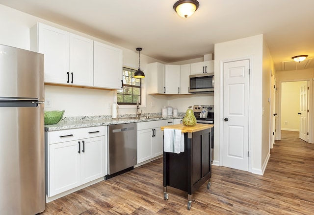 kitchen with wooden counters, appliances with stainless steel finishes, pendant lighting, a center island, and white cabinetry