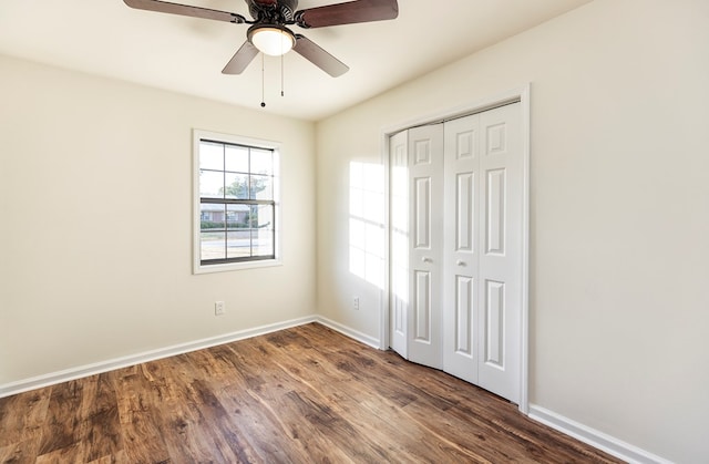 unfurnished bedroom with dark hardwood / wood-style flooring, ceiling fan, and a closet