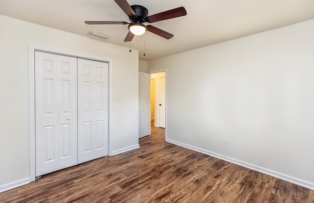 unfurnished bedroom featuring dark hardwood / wood-style flooring, ceiling fan, and a closet