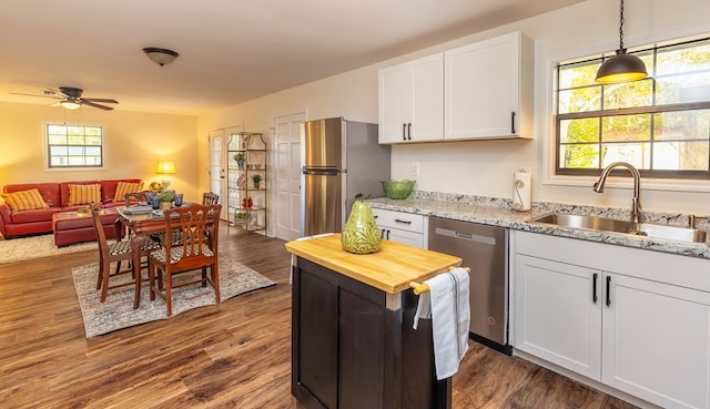 kitchen featuring sink, dark hardwood / wood-style floors, pendant lighting, white cabinets, and appliances with stainless steel finishes