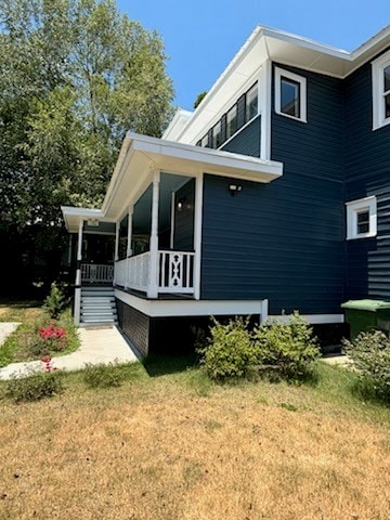 view of property exterior featuring a lawn and covered porch