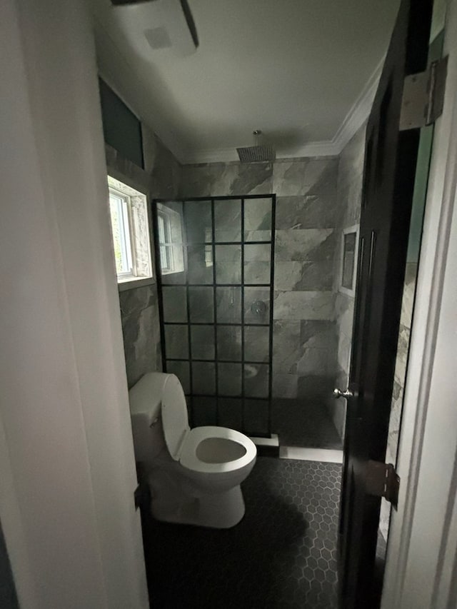 bathroom featuring a tile shower, toilet, and tile walls