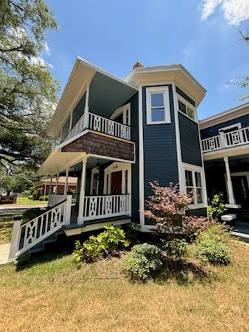 view of property exterior with a porch, a balcony, and a yard