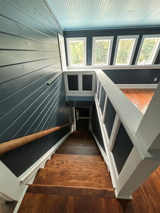 stairs featuring hardwood / wood-style floors, a wealth of natural light, lofted ceiling, and wood walls