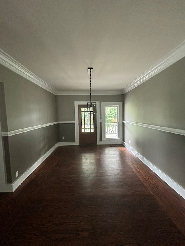 empty room featuring dark hardwood / wood-style floors, crown molding, and a chandelier