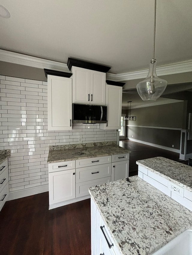 kitchen featuring light stone countertops, hanging light fixtures, dark hardwood / wood-style flooring, decorative backsplash, and white cabinets