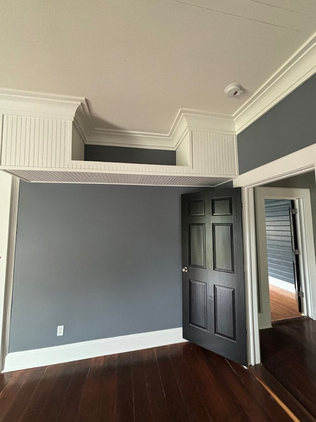 unfurnished bedroom featuring crown molding and dark wood-type flooring