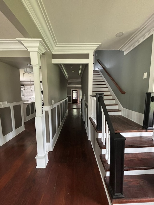 corridor with an inviting chandelier, crown molding, and dark wood-type flooring