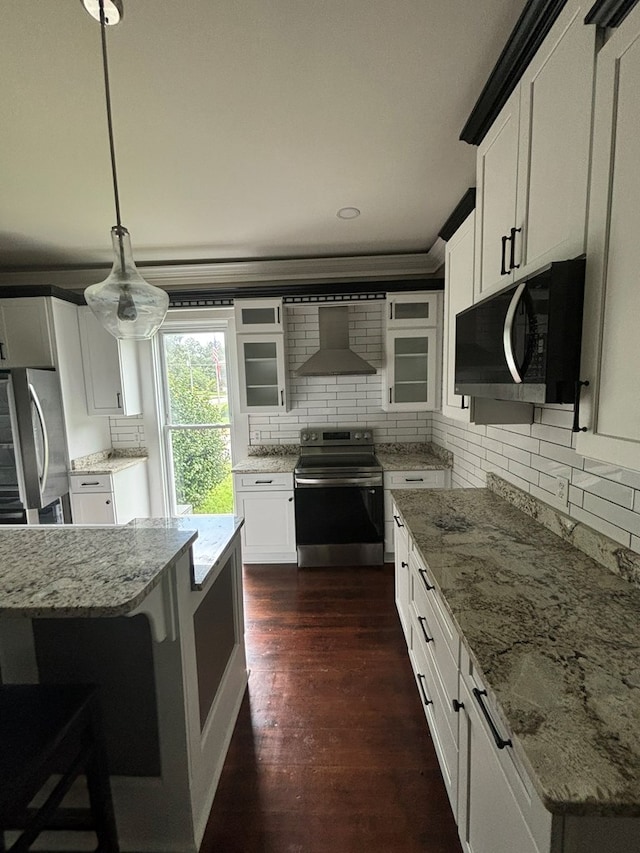 kitchen featuring stainless steel appliances, wall chimney range hood, pendant lighting, white cabinets, and dark hardwood / wood-style floors