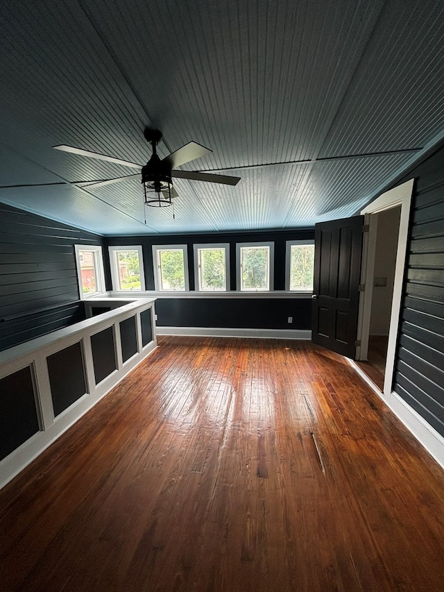 additional living space featuring ceiling fan, hardwood / wood-style floors, and wood walls