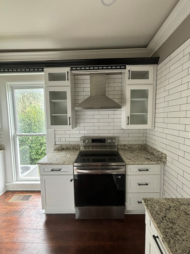 kitchen with decorative backsplash, light stone counters, wall chimney exhaust hood, electric range, and white cabinets