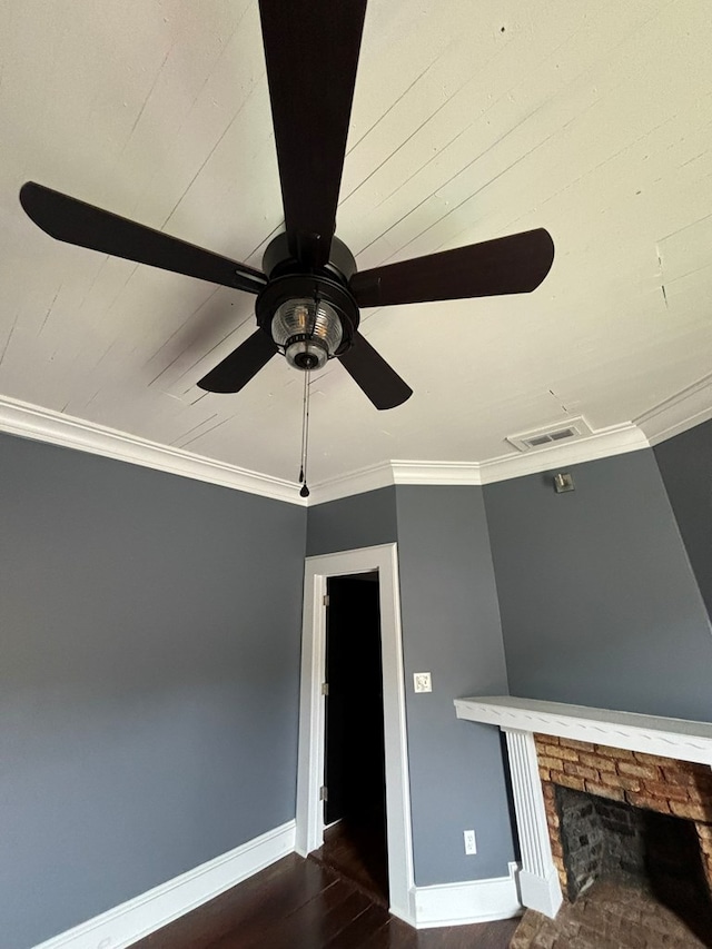 room details with a fireplace, wood-type flooring, ceiling fan, and crown molding