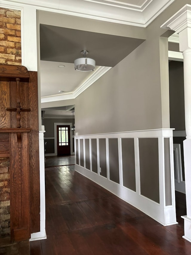 hall featuring dark hardwood / wood-style floors, ornamental molding, and decorative columns