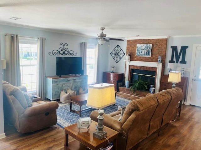 living room with hardwood / wood-style flooring, a brick fireplace, ceiling fan, and ornamental molding