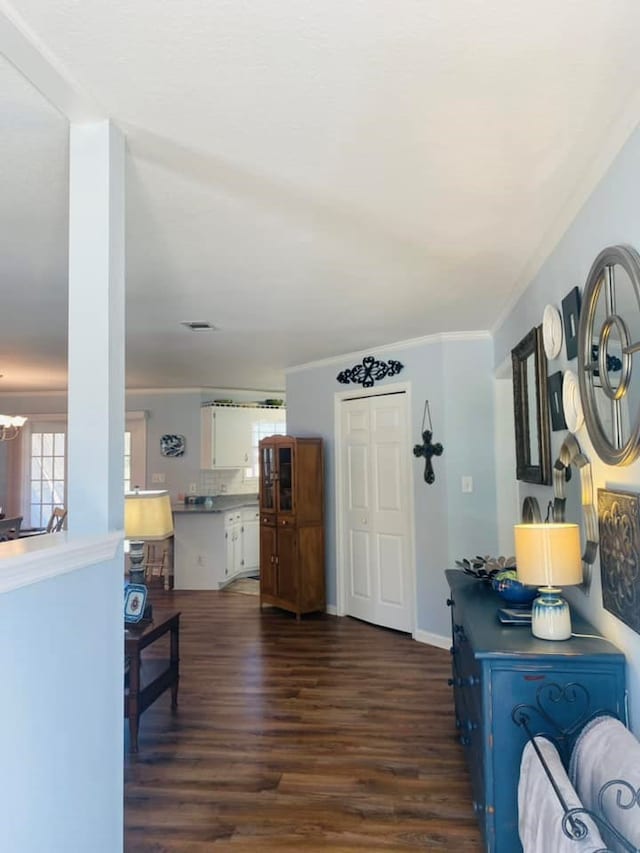 interior space featuring crown molding, dark wood-type flooring, and a notable chandelier