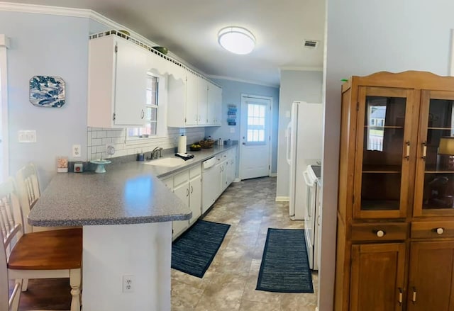 kitchen with tasteful backsplash, kitchen peninsula, crown molding, white appliances, and white cabinets