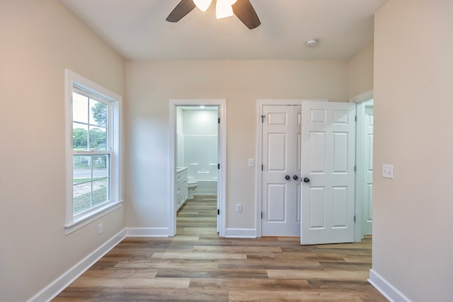 unfurnished bedroom with ceiling fan, light wood-type flooring, connected bathroom, and a closet