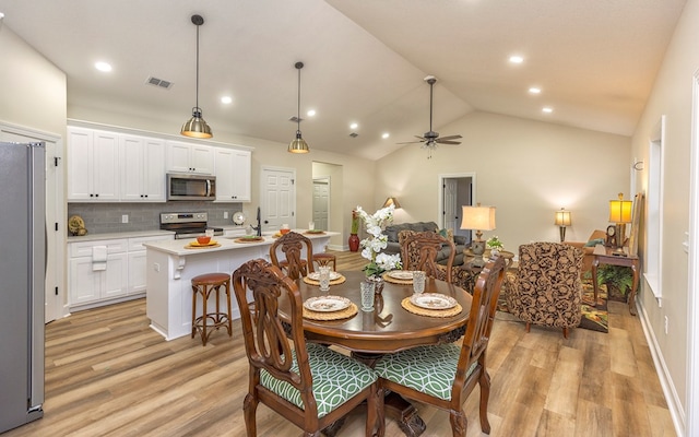 dining area with ceiling fan, light hardwood / wood-style floors, sink, and vaulted ceiling