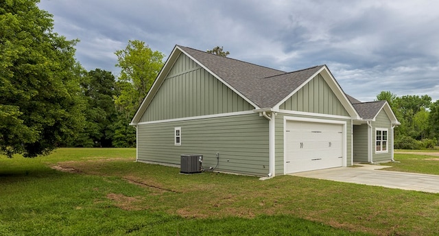 view of side of property with a yard, central AC, and a garage