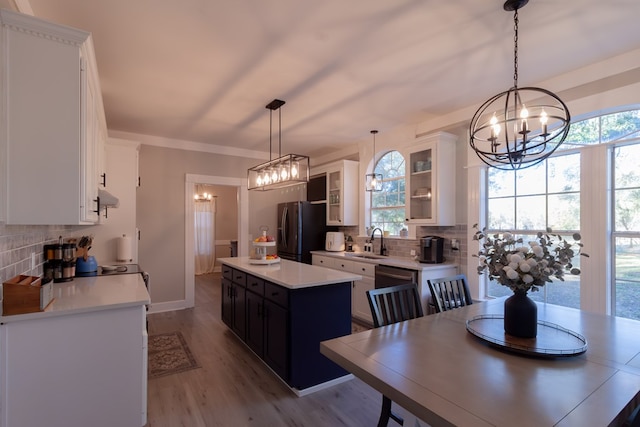 kitchen with a kitchen island, a sink, light countertops, black refrigerator with ice dispenser, and a chandelier