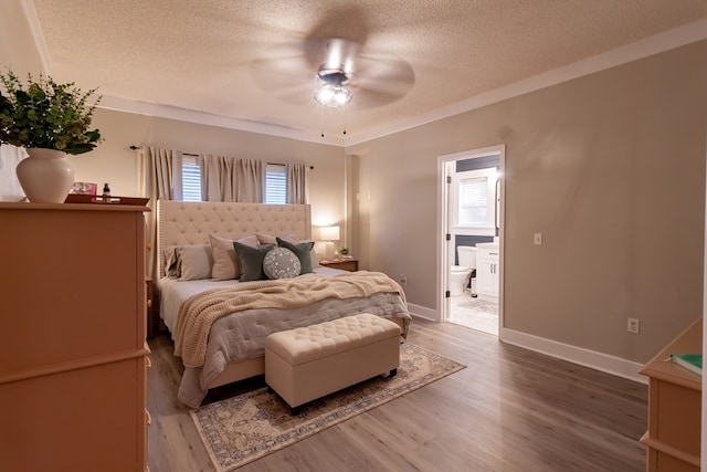 bedroom featuring ensuite bathroom, a textured ceiling, wood finished floors, baseboards, and ceiling fan