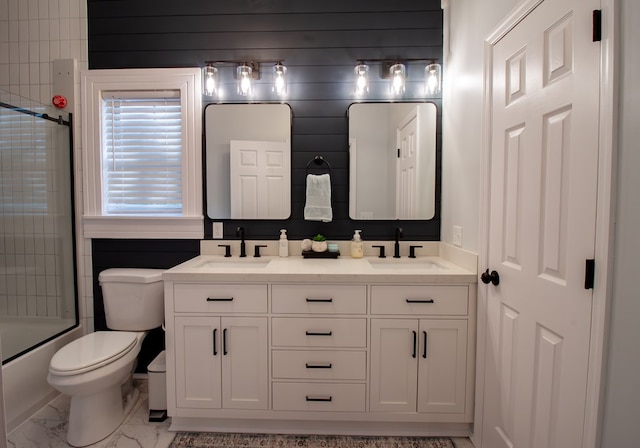 full bathroom with double vanity, marble finish floor, toilet, and a sink