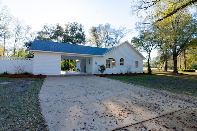 ranch-style house featuring an attached carport, driveway, a front lawn, and fence