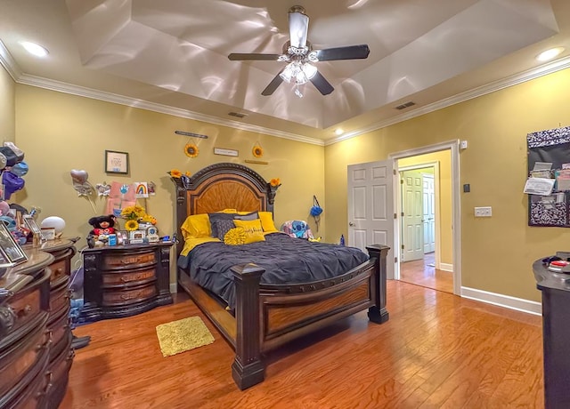 bedroom featuring crown molding, a tray ceiling, wood-type flooring, and ceiling fan