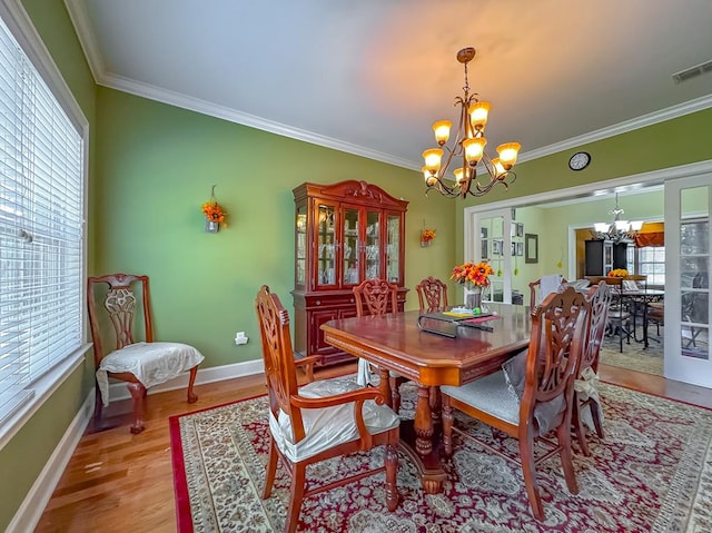 dining area with ornamental molding, a chandelier, and light hardwood / wood-style flooring