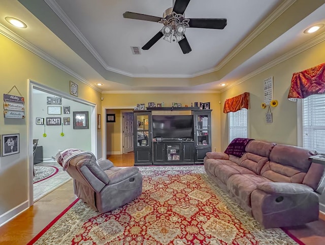 living room featuring crown molding, ceiling fan, light wood-type flooring, and a tray ceiling