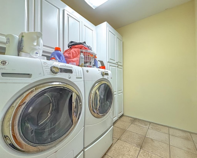 clothes washing area with washer and dryer, light tile patterned floors, and cabinets