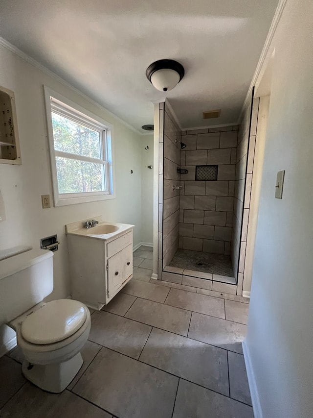 bathroom with a tile shower, vanity, toilet, and ornamental molding