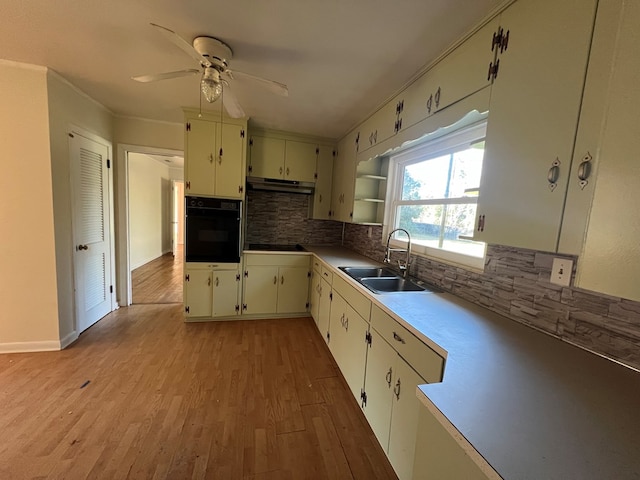 kitchen with sink, oven, tasteful backsplash, light hardwood / wood-style floors, and stovetop