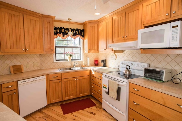 kitchen featuring pendant lighting, sink, white appliances, light hardwood / wood-style flooring, and decorative backsplash