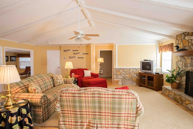 living room with ceiling fan, a stone fireplace, and lofted ceiling with beams