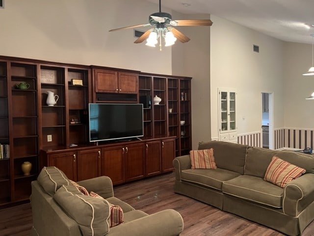 living room featuring dark hardwood / wood-style flooring, high vaulted ceiling, and ceiling fan