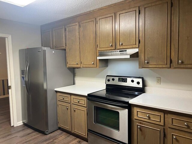 1355 SE Brookwood Dr, Cairo, GA 39828 - kitchen featuring under cabinet range hood, dark wood-style flooring, appliances with stainless steel finishes, and light countertops