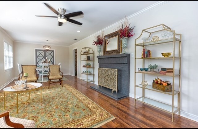 living area featuring crown molding, a fireplace, ceiling fan, and dark hardwood / wood-style floors