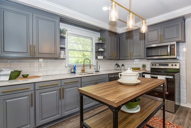 kitchen featuring gray cabinetry, sink, hanging light fixtures, dark hardwood / wood-style floors, and stainless steel appliances