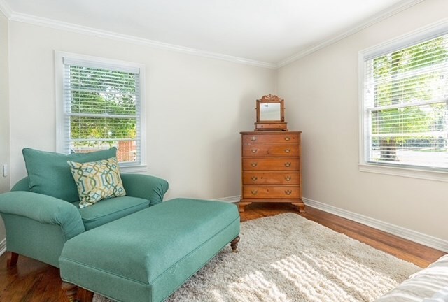 sitting room with wood-type flooring, ornamental molding, and a wealth of natural light