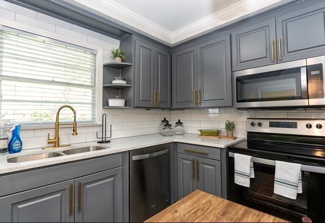 kitchen featuring appliances with stainless steel finishes, tasteful backsplash, ornamental molding, sink, and gray cabinets