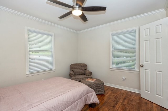 bedroom featuring multiple windows, ceiling fan, crown molding, and dark hardwood / wood-style floors