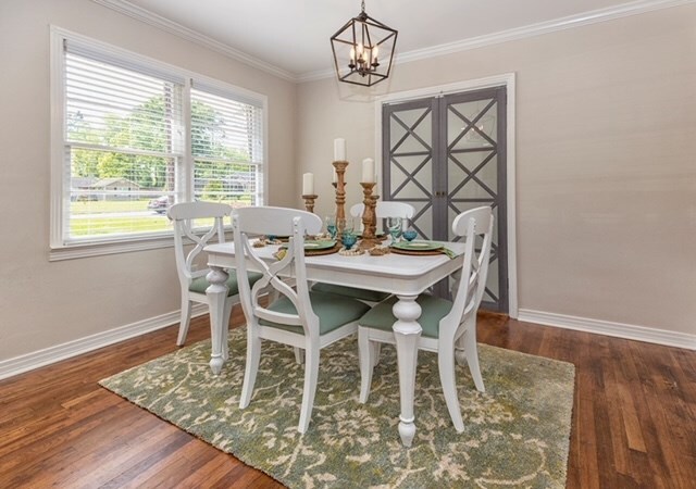 dining room featuring ornamental molding, dark hardwood / wood-style flooring, and a notable chandelier